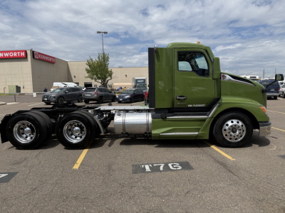Kenworth T680 truck side view with bright green cab and chassis, showing wheels, fuel tanks, and exhaust area.