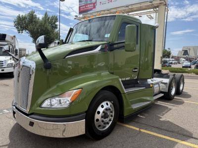 Kenworth T680 truck in green cab, front-left view, showing wheel, chrome bumper, side mirror, and part of the engine hood with badge.