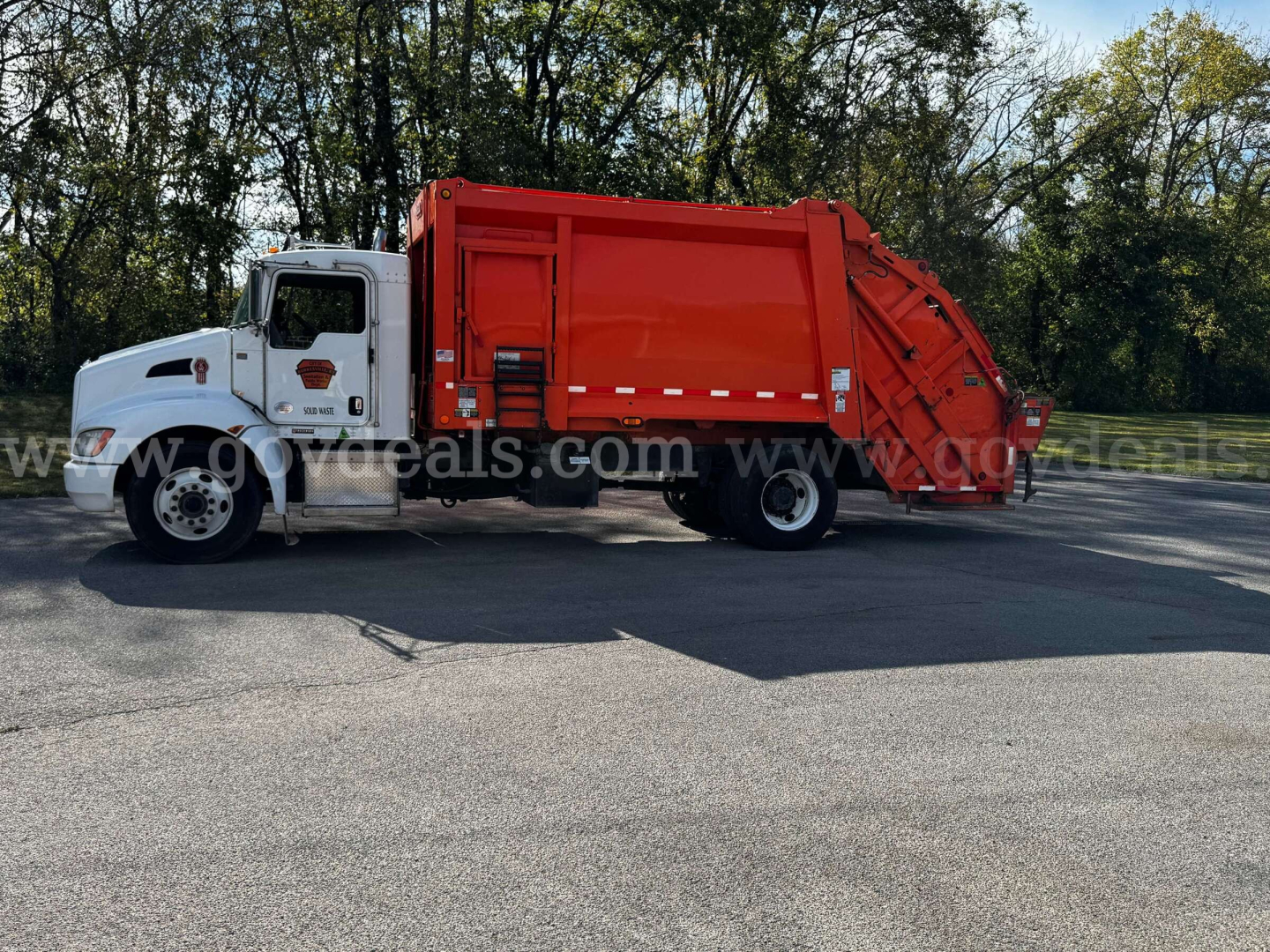 Kenworth T370 garbage truck with white cab and red rear compactor, side view.