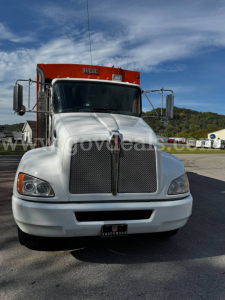 Truck cab front view of a white 2017 Kenworth T370 with a large chrome grille, black windshield, orange top beacon, and side mirrors.