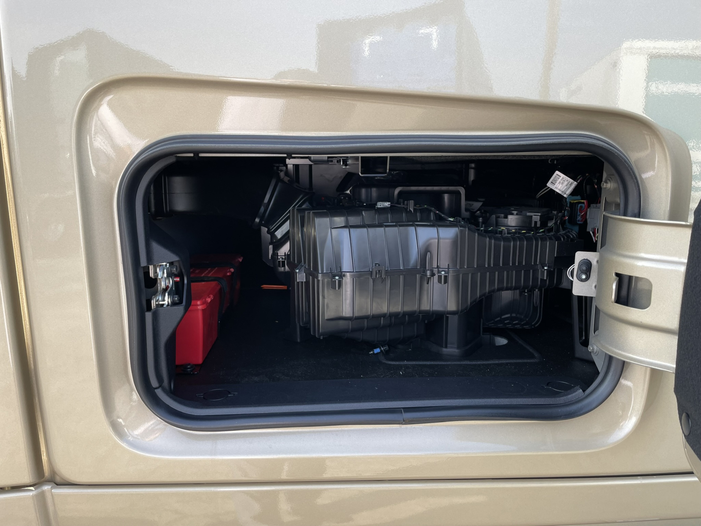 Truck fuel/air system compartment view showing battery red case and black plastic intake/airbox in a Volvo VNL64T860 engine bay side door access