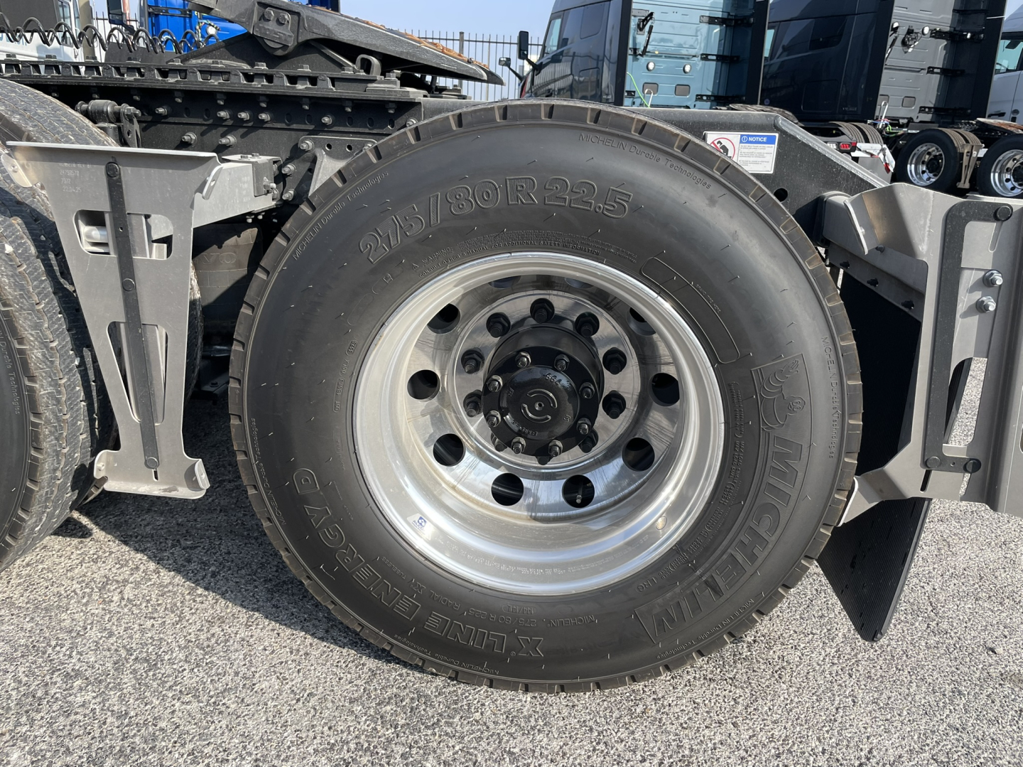 Volvo VNL64T860 tractor wheel with tire and rim, side view showing wheel hub and suspension components.