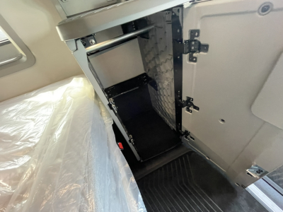 Volvo VNL64T860 cabin storage area with open cabinet door, interior panels, and diamond plate metal backing, showing compartments and hinge hardware.