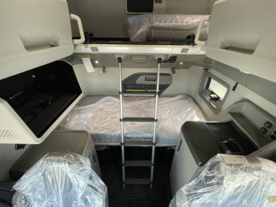 Volvo VNL64T860 sleeper cab interior view with bunk bed, ladder, and plastic-wrapped seats.