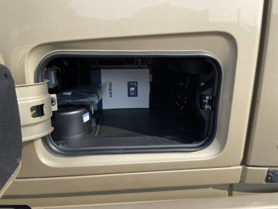 Volvo VNL64T860 truck storage compartment showing mounted XANTREX auxiliary unit and black battery housing.