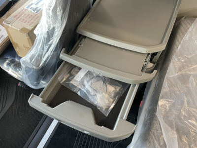Truck interior storage compartments and drawers in a Volvo VNL64T860 sleeper cab showing multiple gray pull-out trays with plastic bags and packaging.