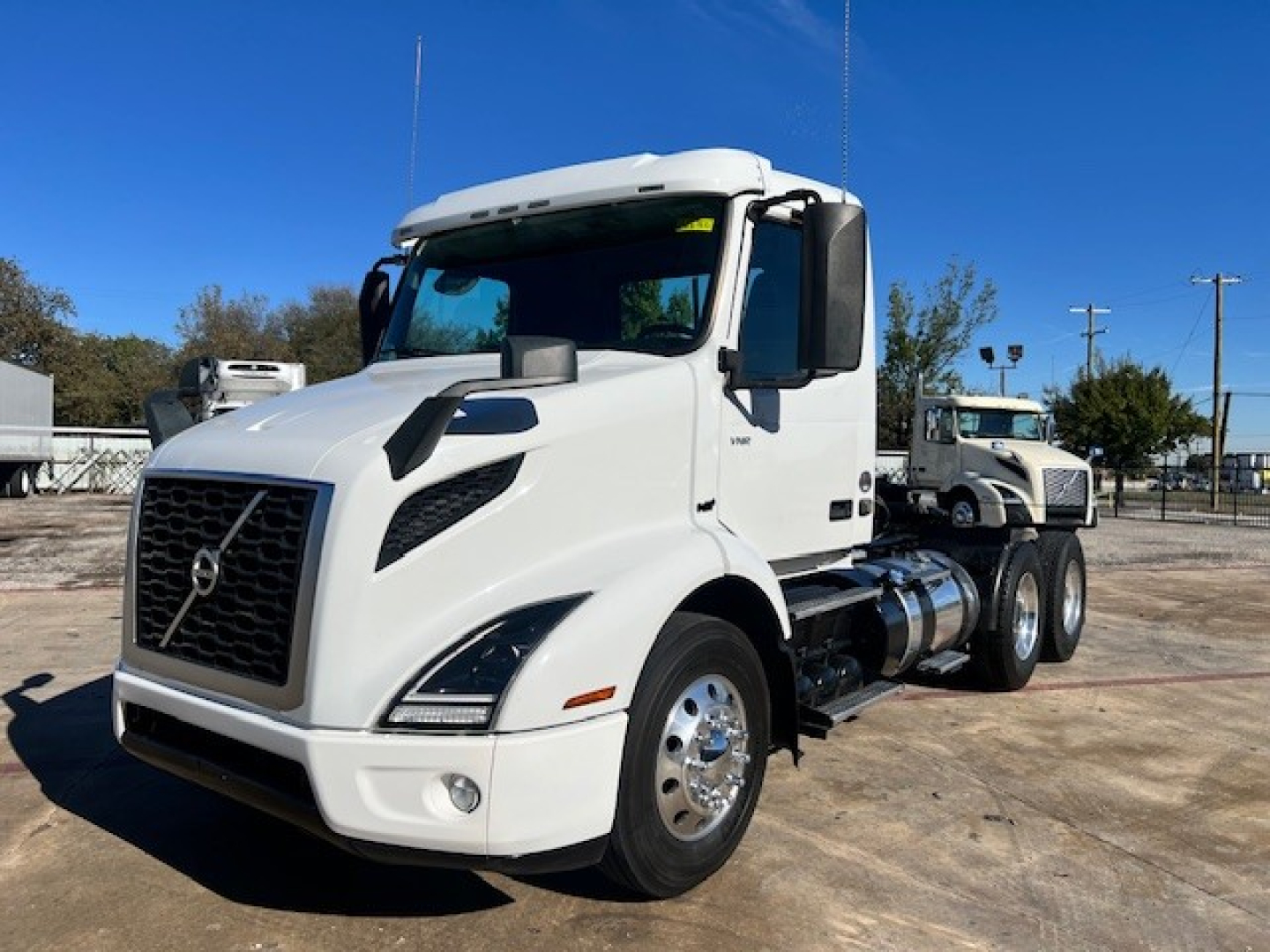 Volvo VNR64T300 conventional daycab truck in white, side view showing large grille, headlights, mirrors, and dual rear axles.