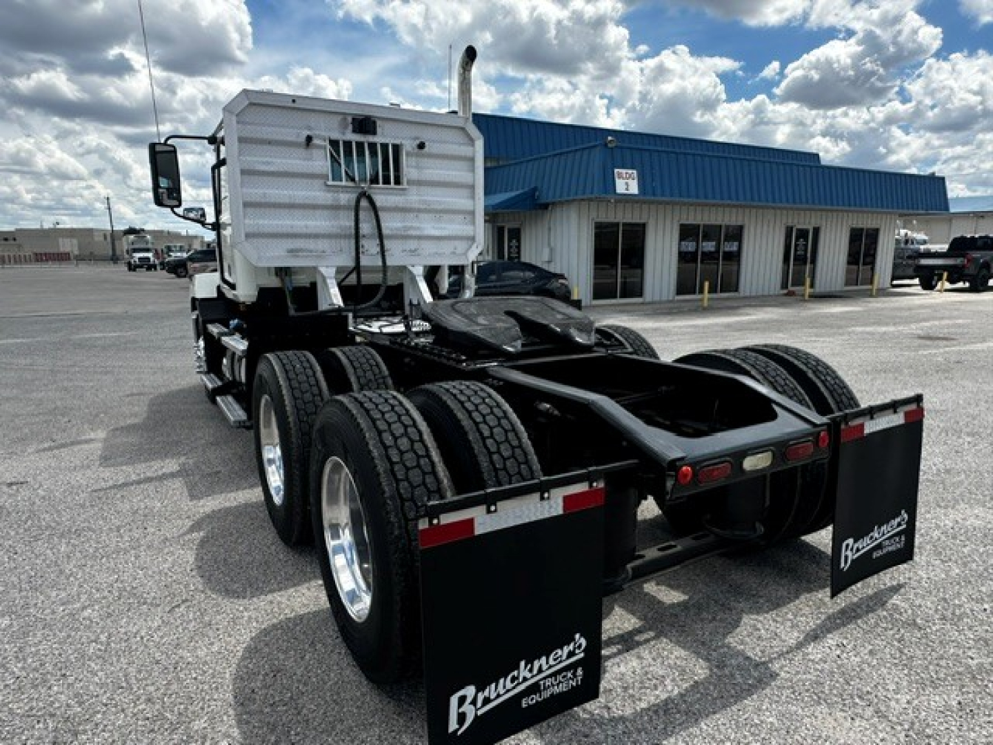 Truck chassis rear view with dual trailer axles and Brackner's logo mud flaps. Sleeper cab visible. 2019 Mack Anthem listing not visible text present.