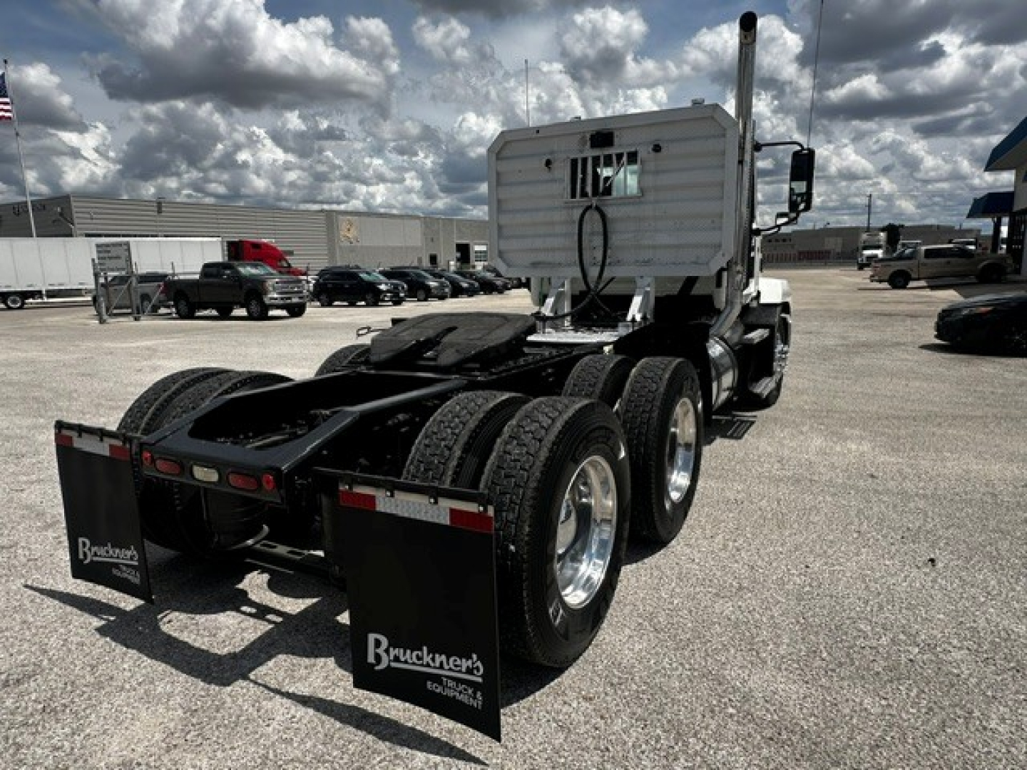 Truck rear view showing dual rear axles and fifth-wheel hitch on a white Mack ANTHEM daycab with mud flaps and Bruckner's plates.