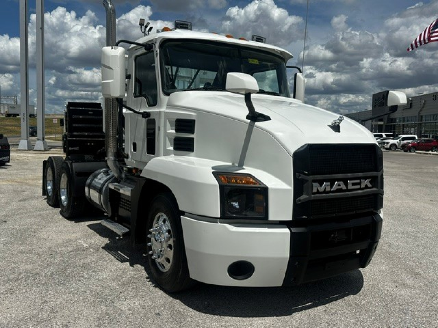 Mack Anthem truck front-left view showing white cab, black grille with MACK logo, dual rear axles, side mirrors, and fuel tanks.