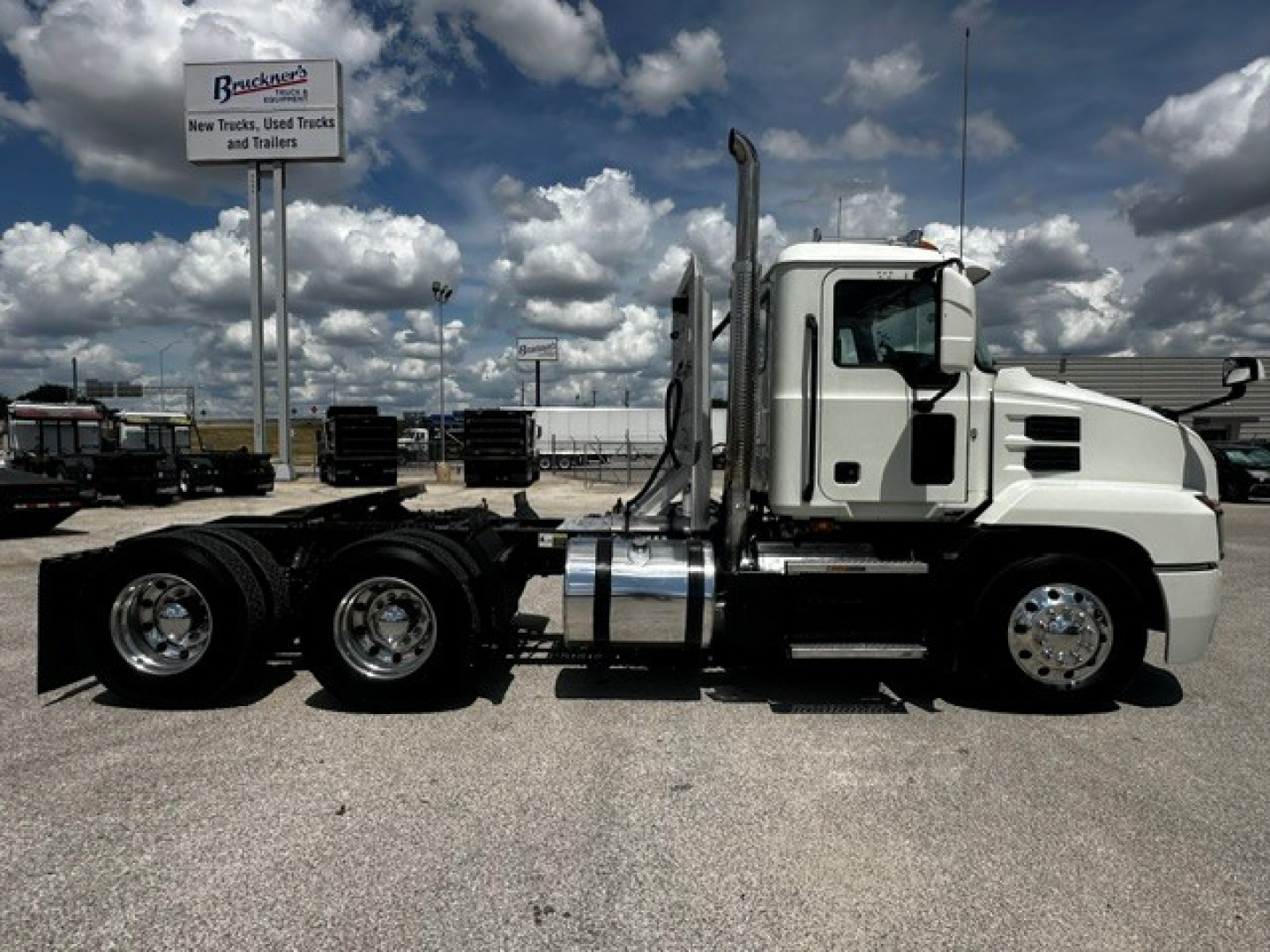 Mack Anthem tractor-trailer side view showing chrome exhaust stacks and fuel tanks with white cab.
