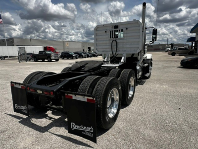 Truck rear view showing dual rear axles and fifth-wheel hitch on a white Mack ANTHEM daycab with mud flaps and Bruckner's plates.