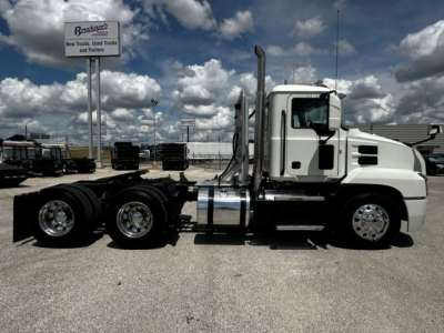 Mack Anthem tractor-trailer side view showing chrome exhaust stacks and fuel tanks with white cab.