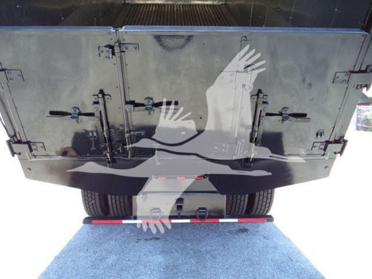 Truck rear showing taillights and undercarriage with black cargo box doors and rear tires.
