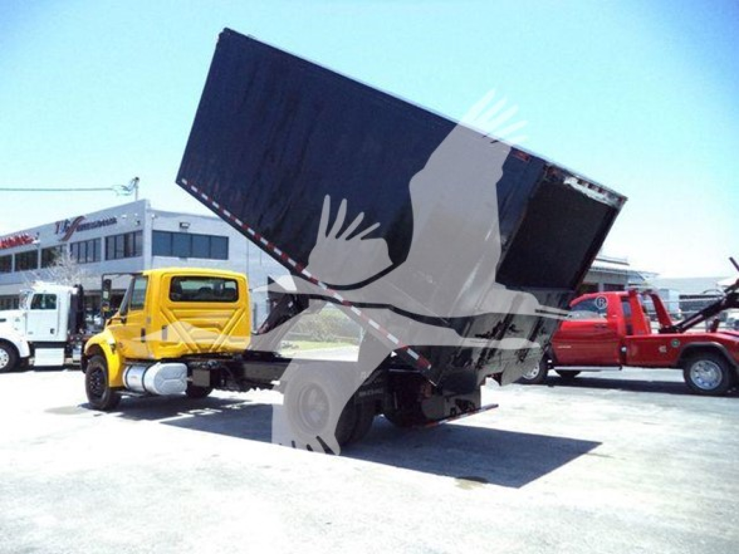 Truck with dump bed raised in a yard, International Durastar 4300 chassis, hydraulic dump on a tilt.
