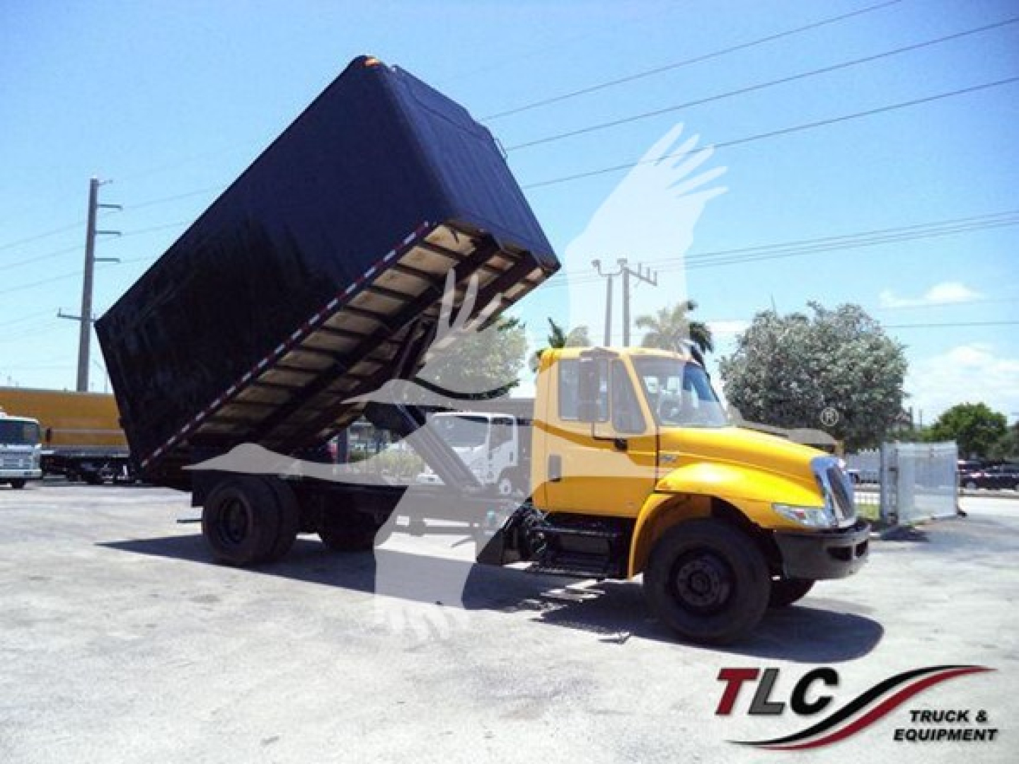 International Durastar 4300 tipping dump truck with a raised black dump bed in a parking lot.