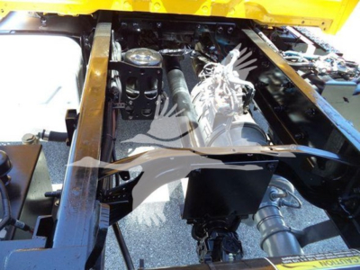 Truck engine bay of a 2019 International Durastar 4300 showing engine components, hoses, and frame; from the top view with yellow body visible.