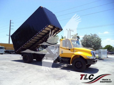 International Durastar 4300 tipping dump truck with a raised black dump bed in a parking lot.