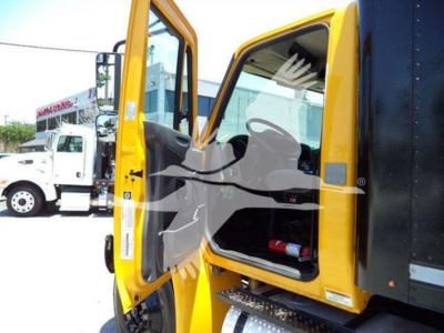 Yellow International Durastar 4300 truck cab with door open; interior visible with a fire extinguisher; other trucks in background.