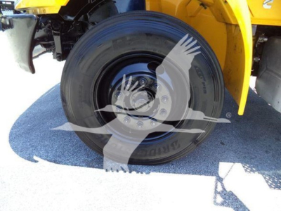 Wheel and tire close-up on a yellow International Durastar 4300 truck chassis showing a black steel wheel and lug nuts.
