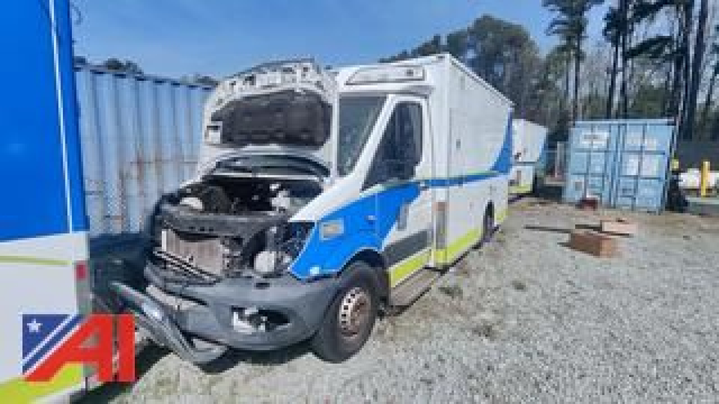 Ambulance van with engine hood open showing front grille and headlights; blue and white livery with yellow stripe.