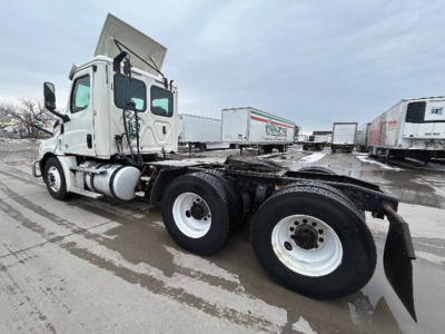 Truck chassis and cab of a Freightliner Cascadia daycab showing rear wheel assembly and exposed frame.