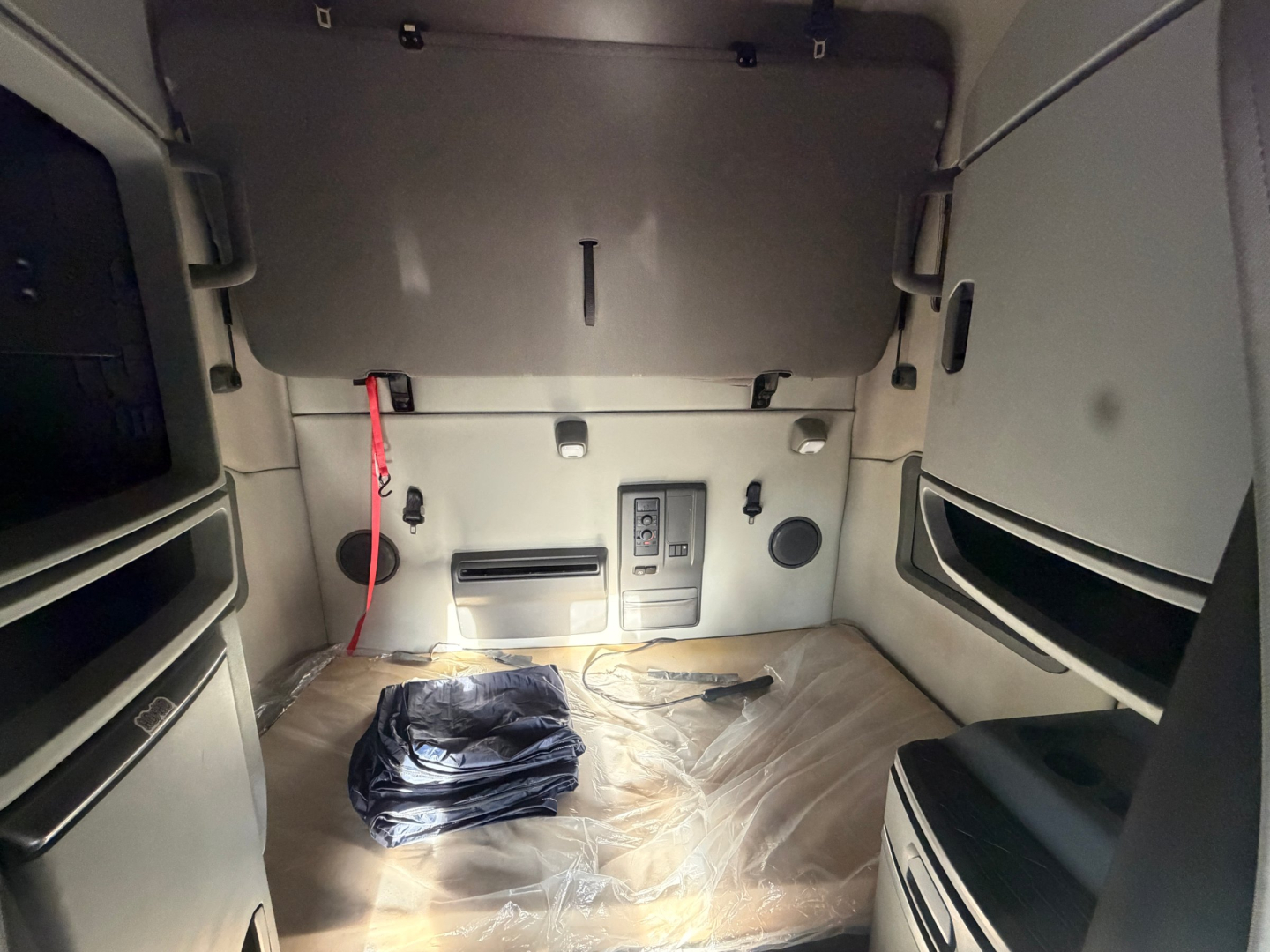 Volvo VNL64T760 sleeper cab interior showing cargo area with floor mat, side panels, and cab controls.