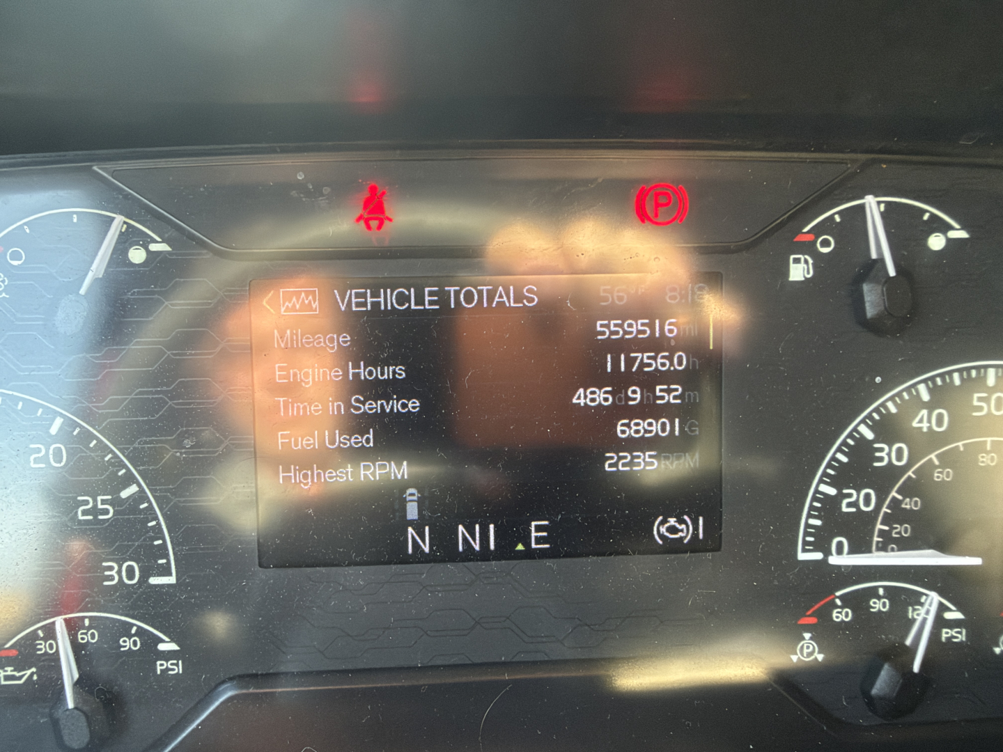 Dash cluster and digital readout showing Vehicle Totals with mileage 559,516, engine hours 11756.0, time in service 486d 9h 52m, fuel Used 68,901, highest RPM 2,235; N N I E gear indicator; various warning lights illuminated.