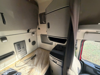 Volvo VNL64T760 cab interior showing side console with storage compartments and window, notables include control panel and plastic seating area.
