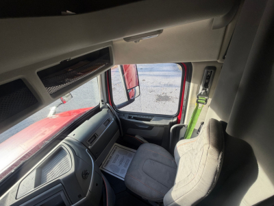  Volvo VNL64T760 truck interior cab view showing seating area and side door, steering column, dashboard, and overhead storage.