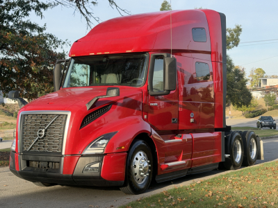 Volvo VNL64T760 tractor in red, front-left view showing cab, grille, headlights, and side mirrors.