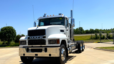 Mack PI64T concrete-color truck cab chassis showing front grille with MACK emblem and dual exhaust stacks.