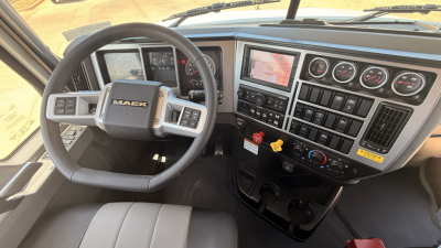 Mack PI64T truck cab interior showing steering wheel dashboard with gauges, digital displays, and control panel.