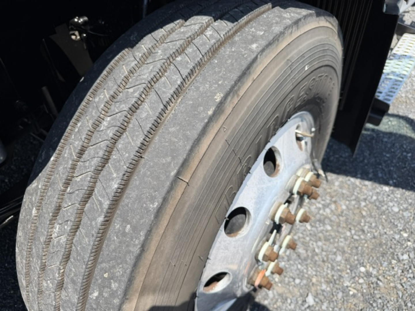 Truck wheel and tire close-up showing wheel hub and lug nuts on a Volvo VNL chassis, with treaded tire and rim detail.