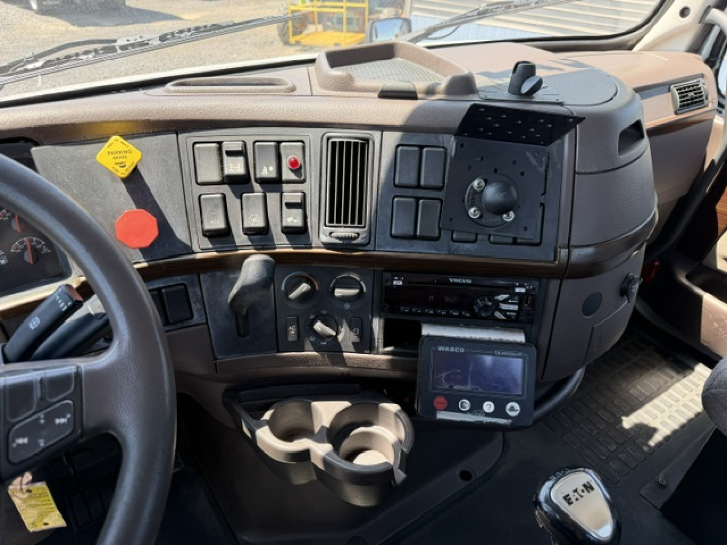 Cab interior of a Volvo VNL64T300 truck showing dashboard controls, steering wheel, center console, and a mounted touchscreen diagnostic display.