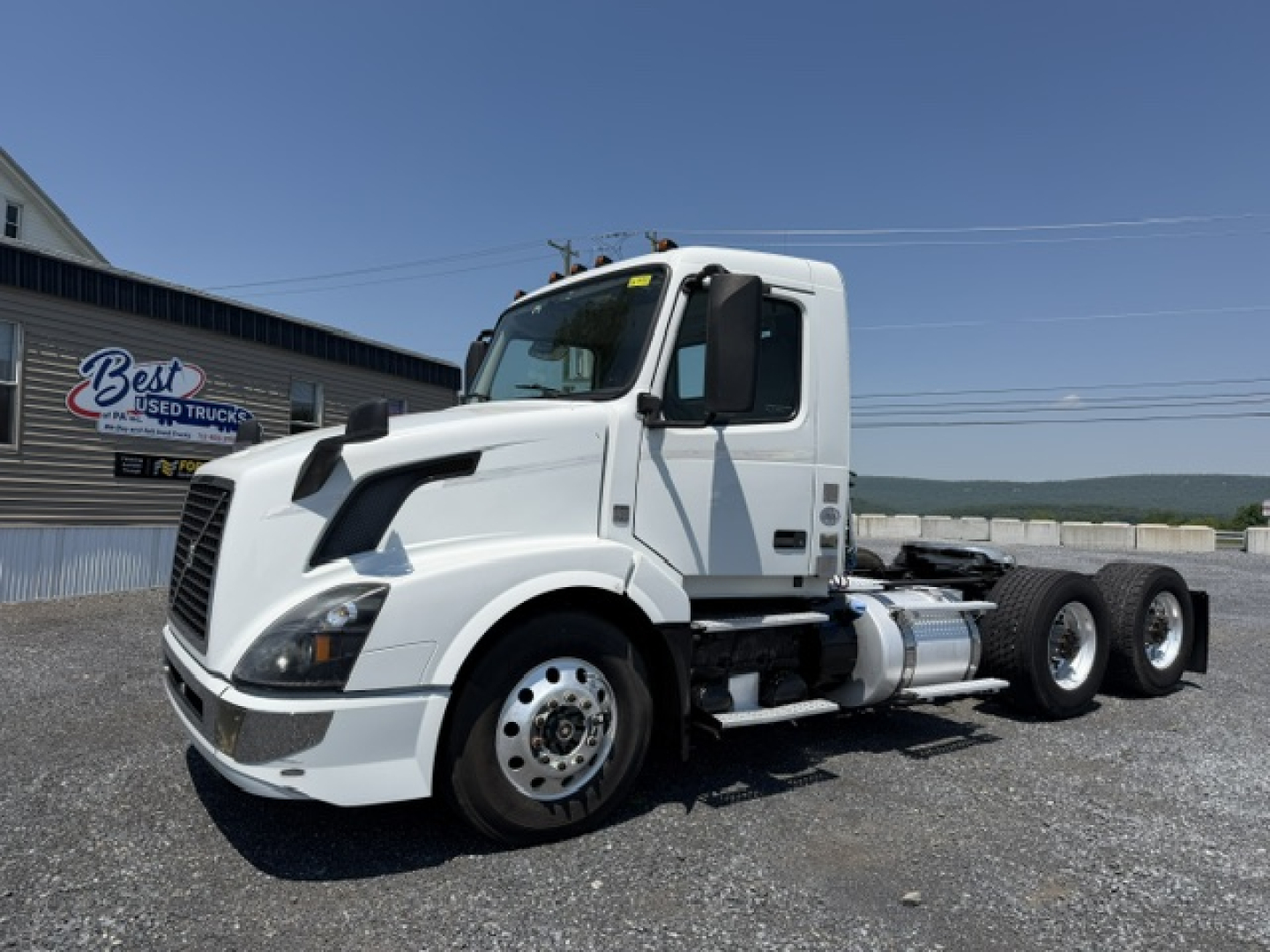 Volvo VNL64T300 day cab truck in white, side view, showing front grille, cab, fuel tanks, and dual rear axles; no visible text on components.