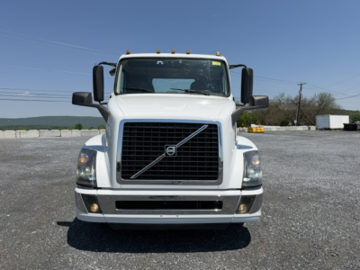 White Volvo VNL64T300 day cab truck front view showing Volvo grille, bumper, headlights and side mirrors.