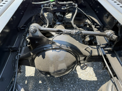 Tractor rear view showing drivetrain and suspension components under a Volvo VNL64T300 truck. Visible parts include differential housing, axles, leaf springs, and drive shaft linkages.