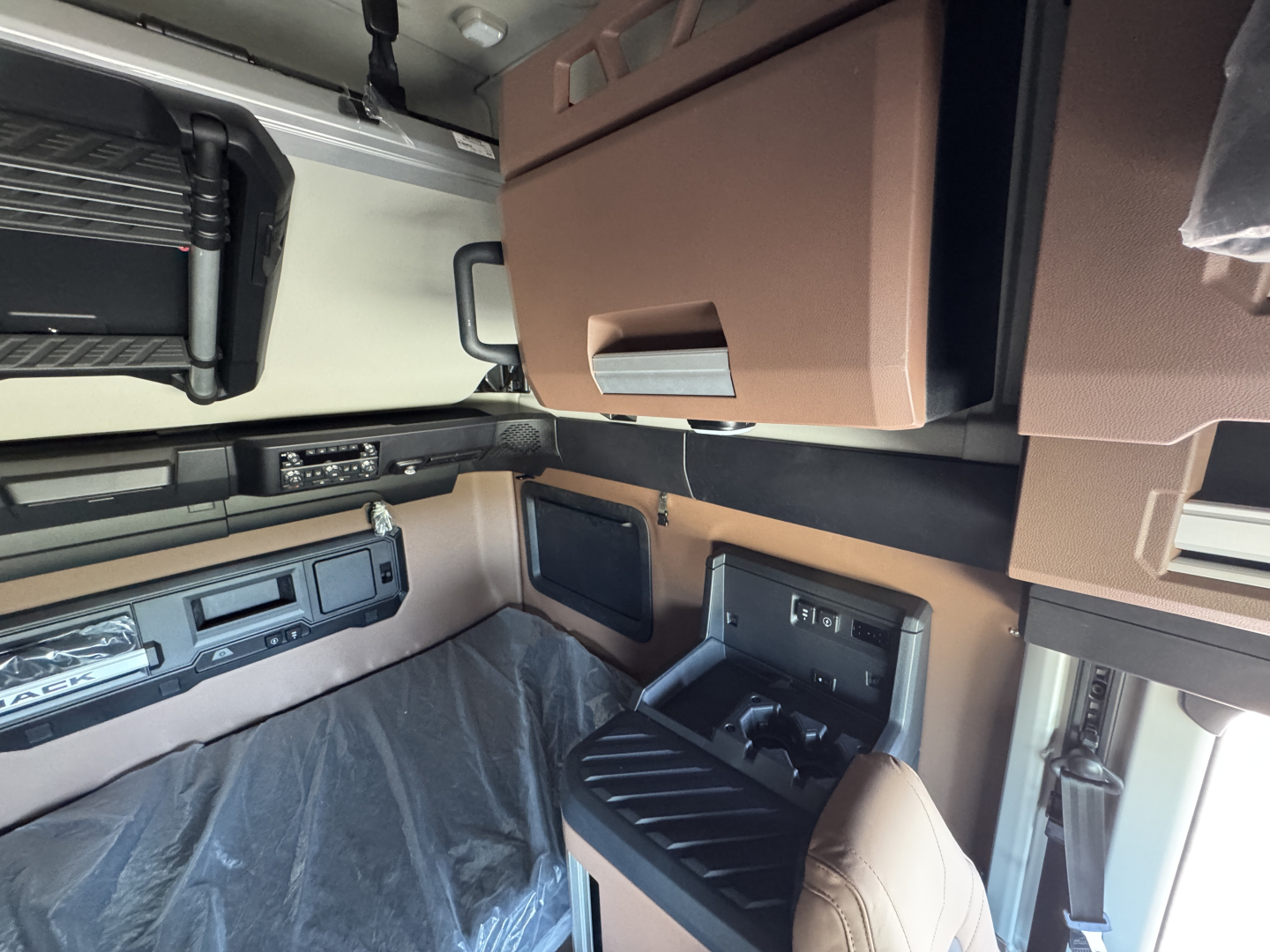 Interior of a Mack PR64T76H cab showing sleeper area, overhead cabinets, dash area, and control panels.