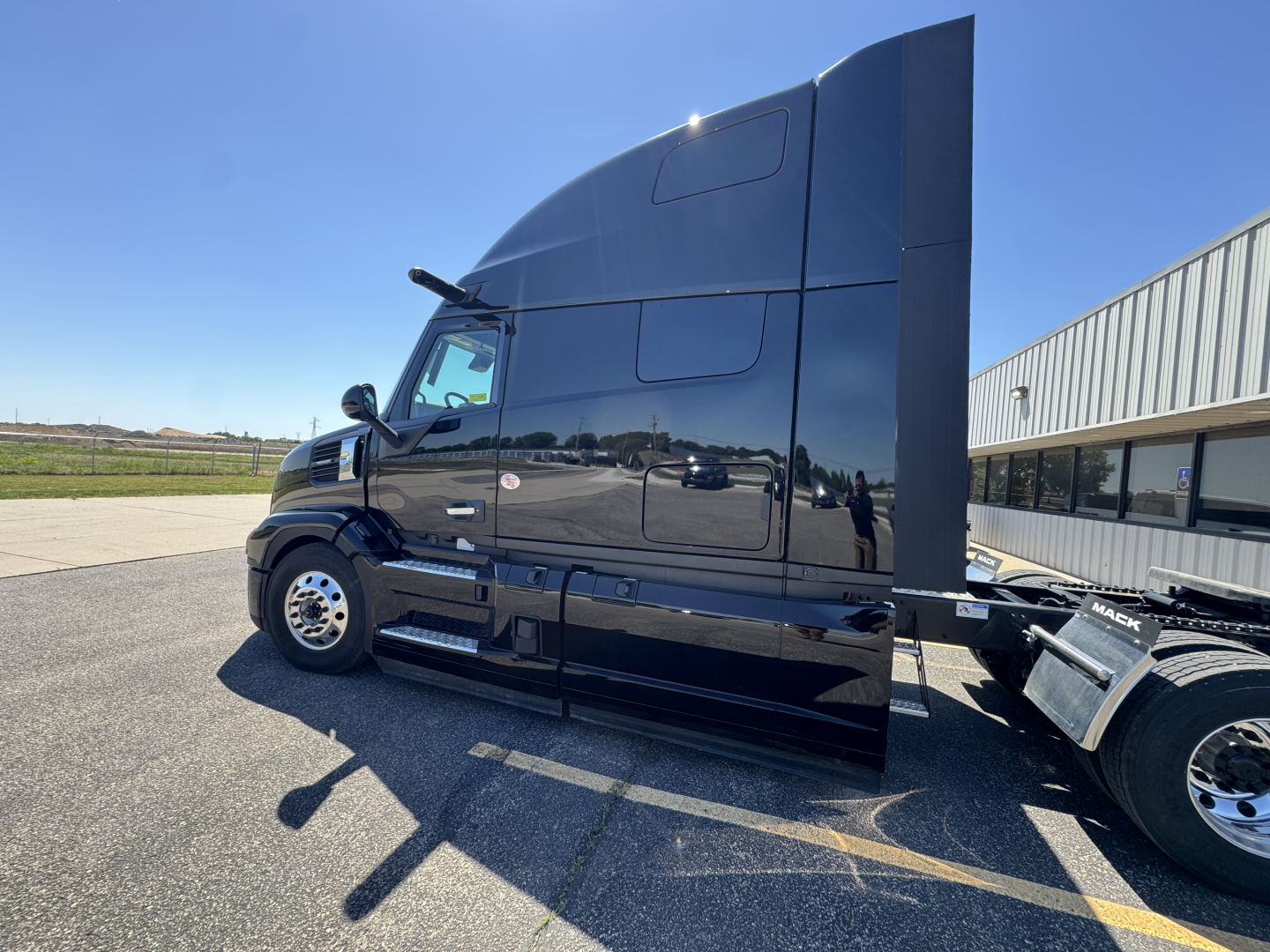 Side view of a black Mack PR64T76H tractor truck with high sleeper, showing the cab and rear section.