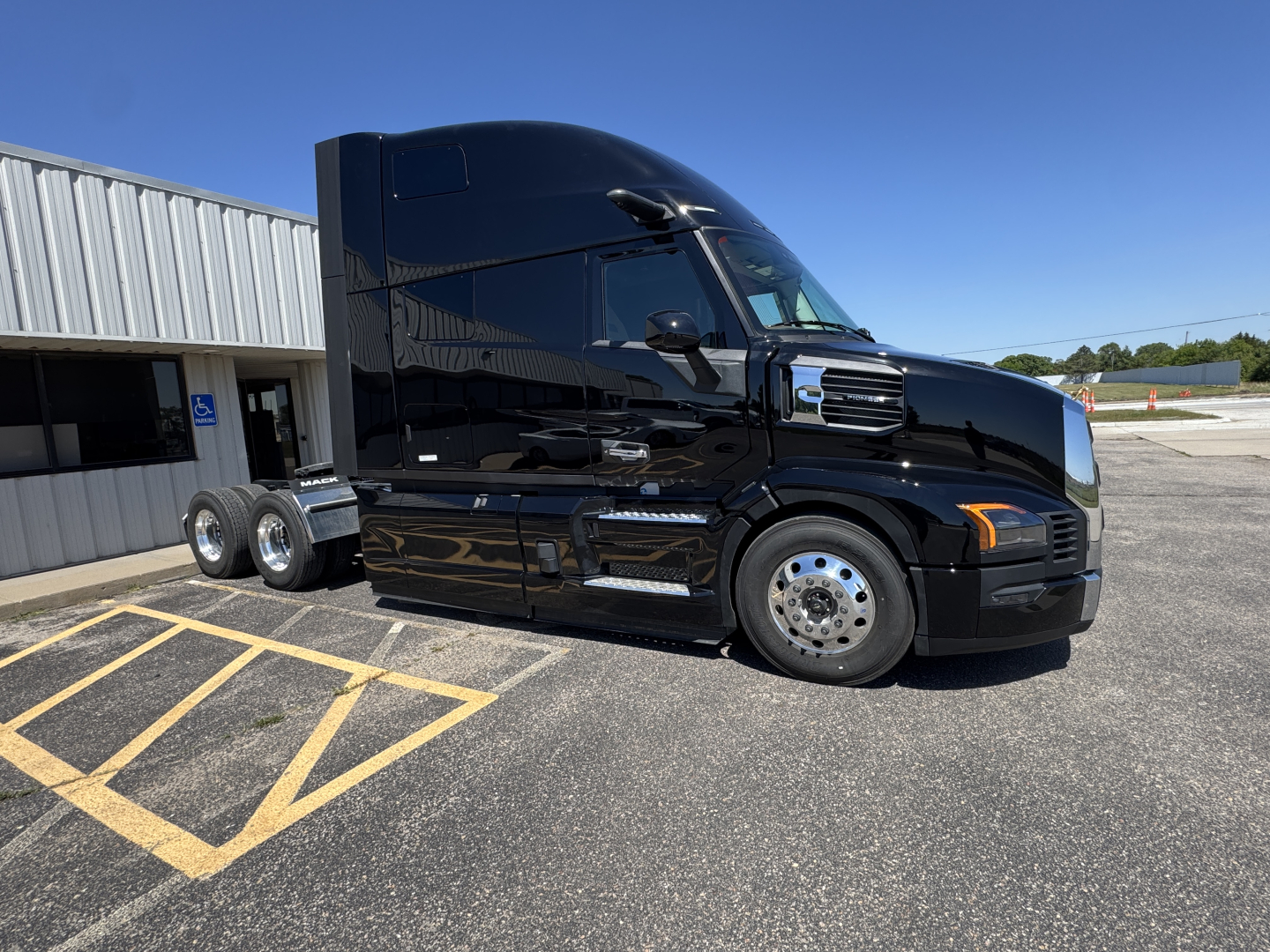 Mack PR64T76H tractor-trailer in black, side view showing sleeper cab and dual rear axles.