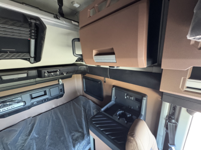 Interior of a Mack PR64T76H cab showing sleeper area, overhead cabinets, dash area, and control panels.
