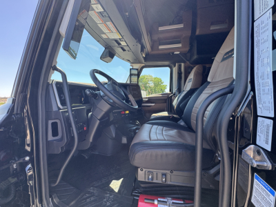 Truck interior cab area with driver seat, steering wheel, dashboard, and entry area. Visible labels on A-pillar and window sticker with small text.