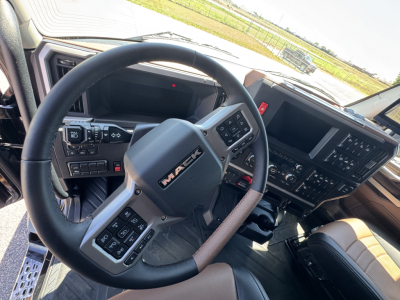 Mack PR64T76H truck interior showing steering wheel with Mack logo, dashboard controls, and center console displays.