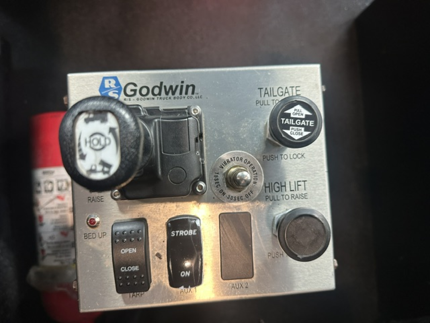 Kenworth T880 dash area with Godwin hydraulic control panel showing tailgate pull handle, high lift, strobe and bed controls.
