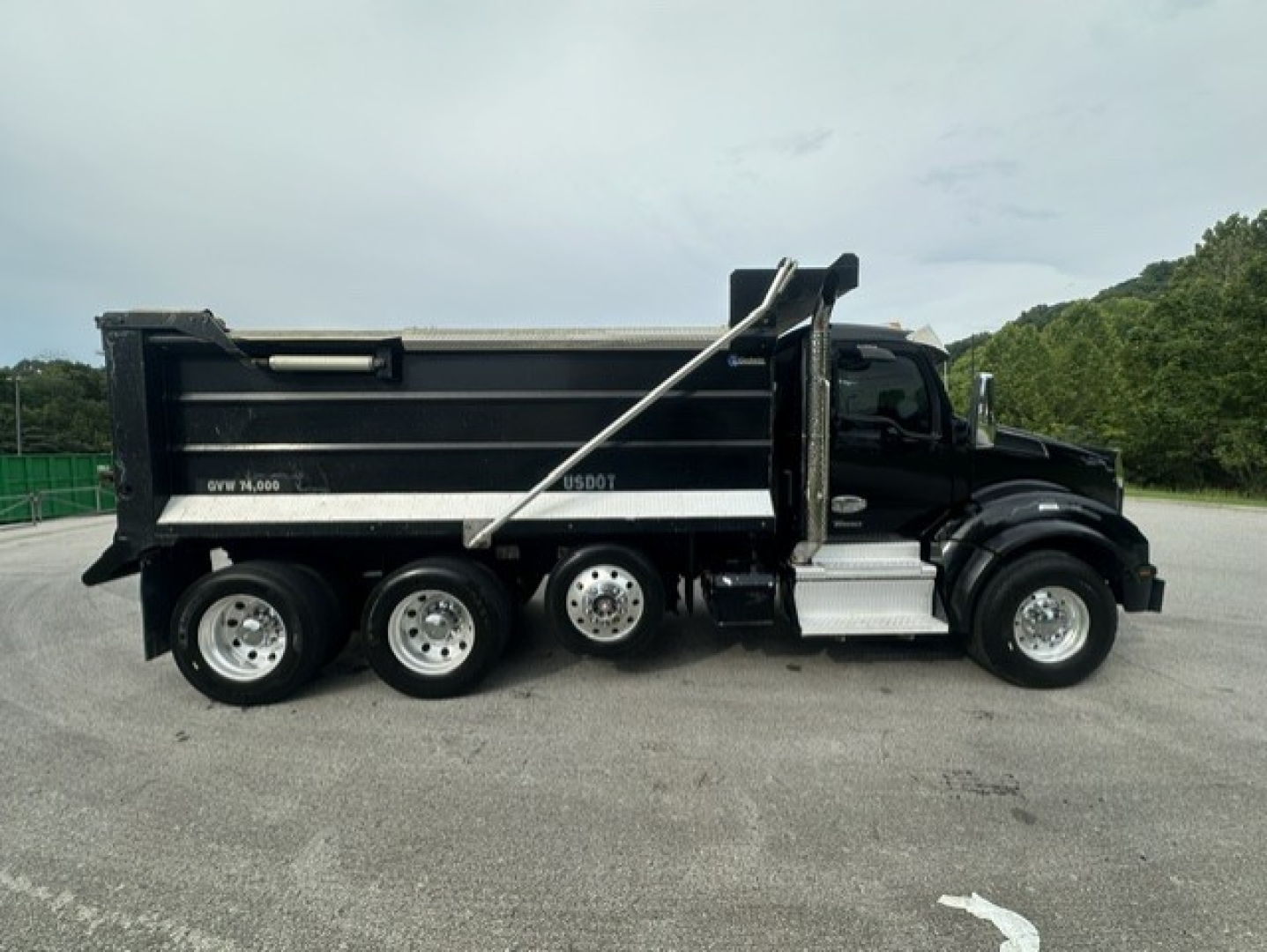 Kenworth T880 dump truck side view showing dump bed and rear wheels.