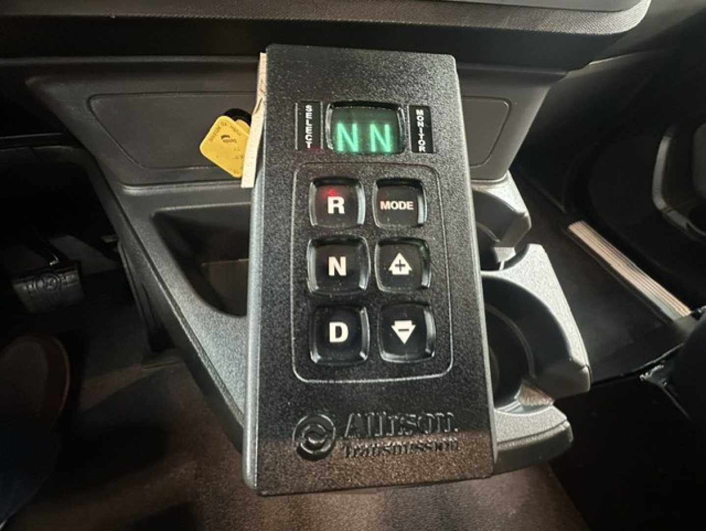Kenworth truck gear shifter panel with push buttons: R, N, D, plus mode and a green N indicator, inside cab.