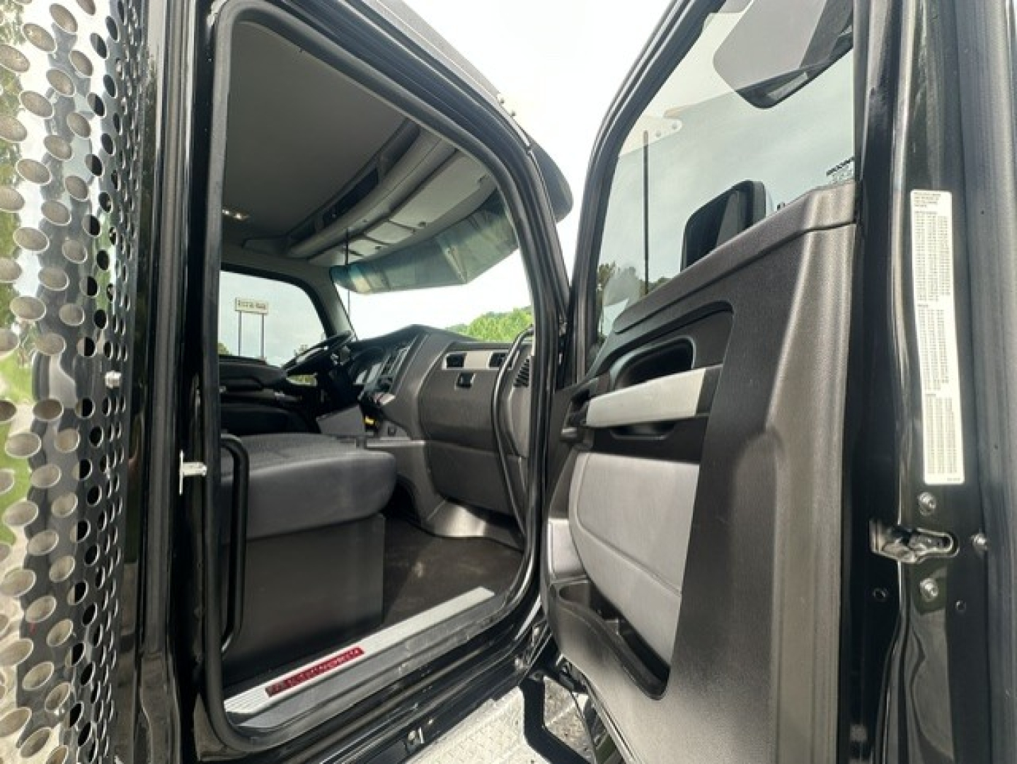 Kenworth T880 cab interior view from open driver door showing dashboard and front seat area.