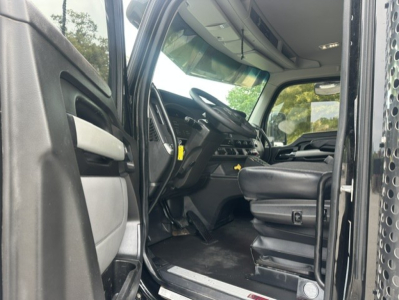 Kenworth T880 truck cab interior with driver seat, dashboard, and open door; steering wheel and controls visible.