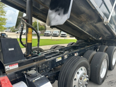 Kenworth T880 dump truck chassis and dual rear axles with hydraulic system visible under dump bed.